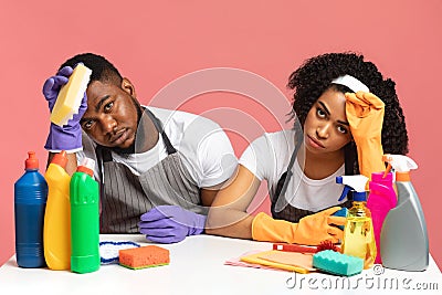 Household Stress. Exhausted couple sitting at table among detergents and cleaning tools Stock Photo