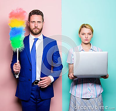 Househusband and female boss. Businessman and housewife. Family couple. Husband stand with dust brush while wife holding Stock Photo