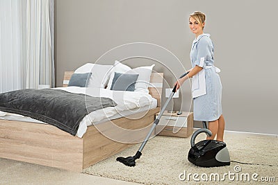 Housekeeper cleaning with vacuum cleaner Stock Photo