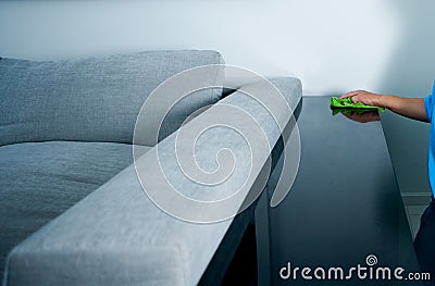 Housekeeper dusting table near couch Stock Photo