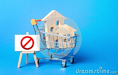 Houses in a shopping cart and easel red prohibition sign NO. Inaccessibility, lack housing, deficit. Seizure, freezing of assets Stock Photo