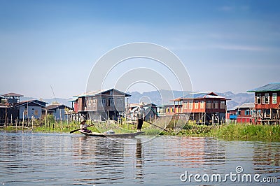 Houses on wood piles and burmese people in a boat in a village at Inle Lake, Burma Myanmar Editorial Stock Photo