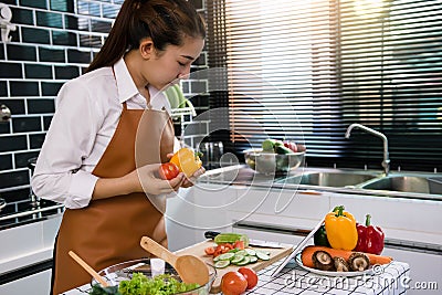 The housewife is cooking by looking at the recipe on the tablet Stock Photo