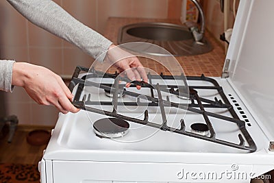 Housewife hold metal grates to clean the dirty kitchen gas stove. Stock Photo