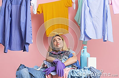 Housewife is looking up, leaning on heap of dirty clothes Stock Photo