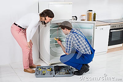 Housewife Looking At Worker Repairing Refrigerator Stock Photo