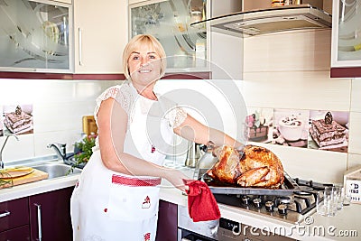 Housewife cooking garnished roasted turkey on Christmas on a kitchen background. Thanksgiving turkey concept. Stock Photo