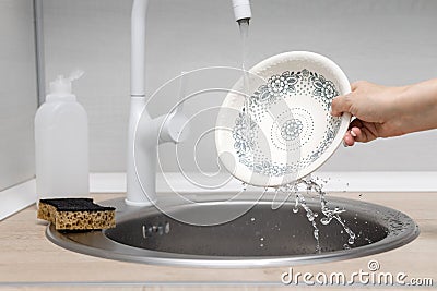 housewife washes a plate in the kitchen sink Stock Photo