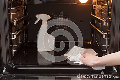 Housework and housekeeping concept. Cleaning the stove and oven. Close up of female hand with dry white napkin wipes clean electri Stock Photo