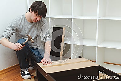 Housing furniture theme. Contractor repairman assembling new furniture in modern apartment Stock Photo