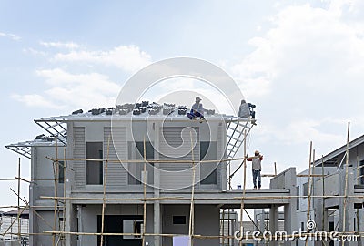 Housing property construction progress, people are building a precast house, the workman working on the roof in a hot day under Stock Photo