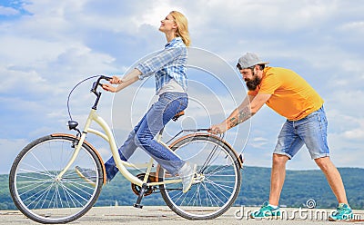 How to learn to ride bike as an adult. Girl cycling while boyfriend support her. Teach adult to ride bike. Man helps Stock Photo