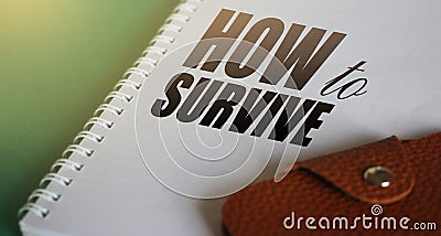 How to survive words on page of copybook and leather wallet. Survival concept. Crisis management business concept. Stock Photo