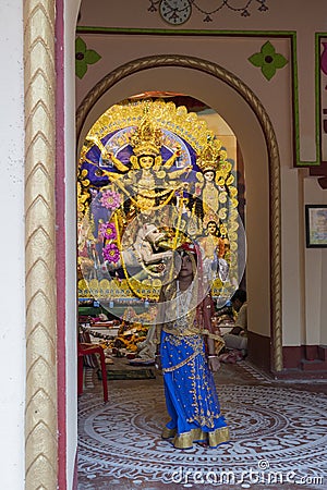 Howrah,India -October 26th,2020 : Bengali girl child posing with Goddess Durga in background, inside old age decorated home. Durga Editorial Stock Photo