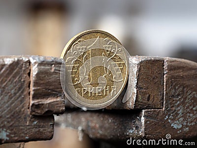 hryvnya coin clamped in a metal vise. Currency and Ukrainian economy under the onslaught, the concept of financial problems Stock Photo
