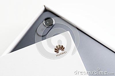 Huawei label on a fragment of a white original box. White background with the unpacking of a gadget with a built-in camera. Photo Editorial Stock Photo