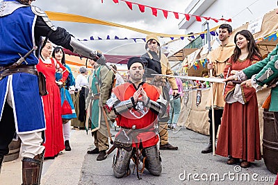 A man dressing as a medieval knight with metallic armor is mading a performance in the parade of Editorial Stock Photo