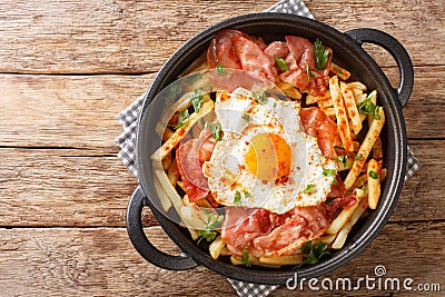 Huevos Rotos with fried potatoes and ham close-up in a plate. Horizontal top view Stock Photo