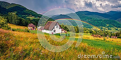 Huge ainbow at the summer rain. Panoramic morning view of Kvasy village, Transcarpathian, Ukraine. Stock Photo