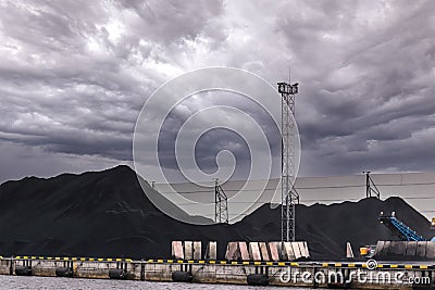 A huge amount of coal in the sea trading port. Coal is delivered here in industrial wagons, distributed throughout the port, Stock Photo