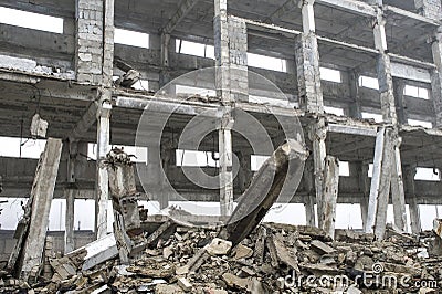 A huge concrete beam sticking out of a pile of concrete debris on the background of the destroyed frame of the building Stock Photo