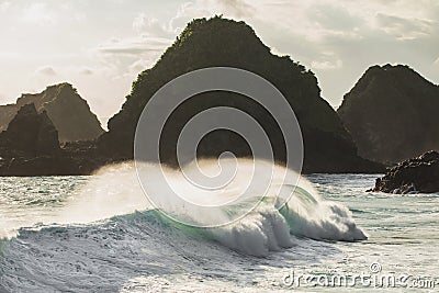 Huge crashing waves in sunset light with mountain view Stock Photo