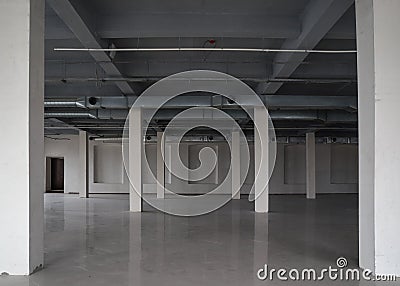 Huge empty storehouse or open space with rows of columns, ceramic floor and pipes under the ceiling Stock Photo