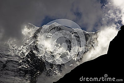 A huge glacier from a very high mountain appears among the clouds in the annapurna of the nepali himalayas Stock Photo