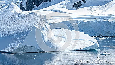 Tiny Penguins on Ice Floe and on Huge Iceberg with Fissure in Antarctica near Petermann Island Stock Photo