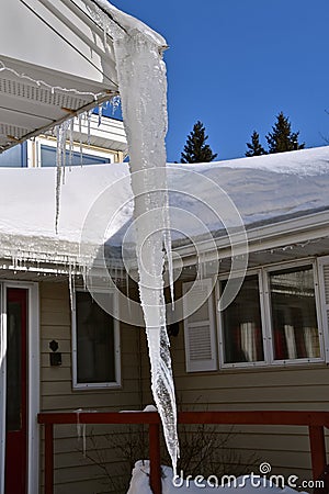 Dangerously huge icicle hanging from an eavestrough Stock Photo