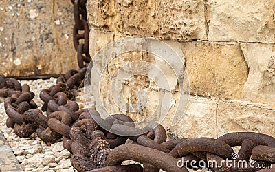 A huge, old and rusty chain hanging down from sandstone wall in Fort St. Elmo, Valletta, Malta Stock Photo