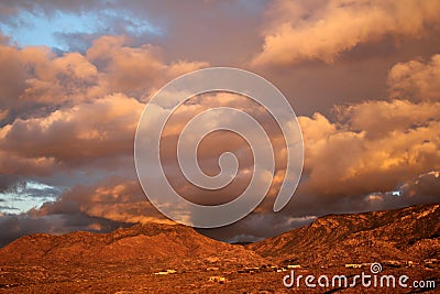 Huge orange monsoon clouds over the deep amber mountains at sunset in Tucson Arizona Stock Photo