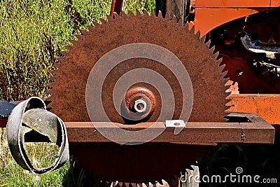 Old rusty saw blade mounted on an orange tractor front Stock Photo