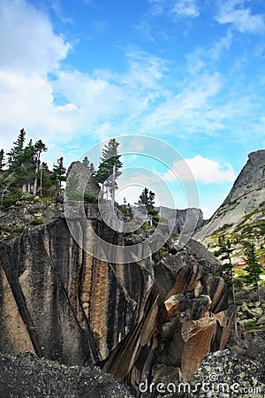 Huge stone block with pines and fir trees on sky Stock Photo