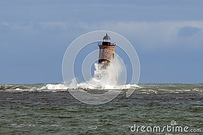 Huge Wave Wraps Around Stone Lighthouse Tower in Maine Stock Photo