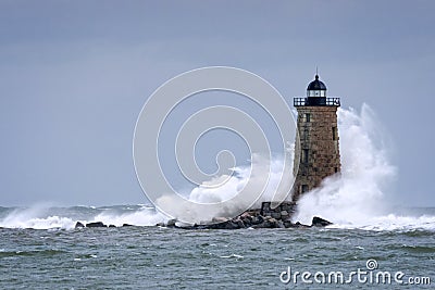 Huge Waves Crashing Around Stone Lighthouse Tower in Maine Stock Photo