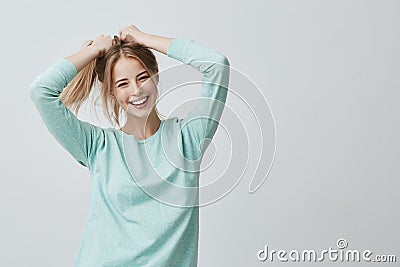 Human face expressions and emotions. Positive young beautiful female with dyed blonde straight hair in ponytail dressed Stock Photo