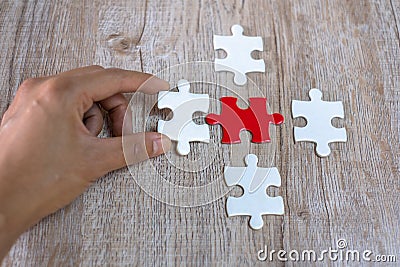The human hand catches the white puzzle Pieces of red and white puzzle on a brown background. Business concept. Success and Stock Photo