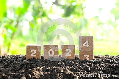 Human hand change year 2023 to 2024 in wooden blocks with growing plant at sunrise. Welcome new year 2024 Stock Photo