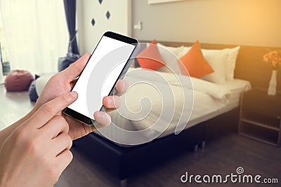 human hand hold smartphone, tablet, cell phone with blurry modern bedroom Stock Photo