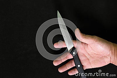 Human hand holding a knife in dark black background. Murder, killer and suicide concept. Stock Photo