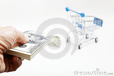 Human hand holds a bundle of 100 dollars bills and shopping cart Stock Photo