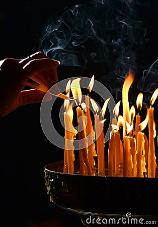 Human hand lights a candle in the church Stock Photo