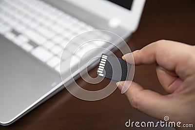 Human hand plugging in an SD media card into the personal laptop computer. Stock Photo