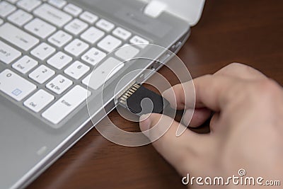 Human hand plugging in an SD media card into the personal laptop computer. Stock Photo