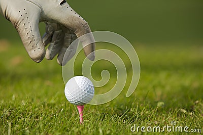 Human hand positioning golf ball on tee, close-up Stock Photo