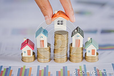 Human hand putting house model on coins stack. Concept for property ladder, mortgage and real estate investment Stock Photo