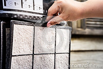 A human hand is removing the filter of an air purifier for filtering PM2.5. To bring a filter to remove dust Stock Photo