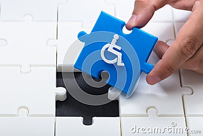 Human hand solving jigsaw puzzle with blue piece Stock Photo