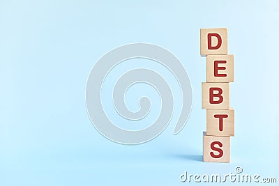 Human hand stacking word debts in wooden blocks. Growing financial debt, pile up, accumulation, stockpile and increase concept. Stock Photo